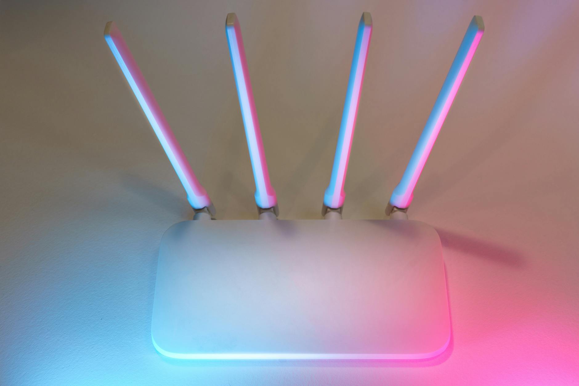 Biały router Wi-Fi z czterema antenami w niebiesko-różowym świetle