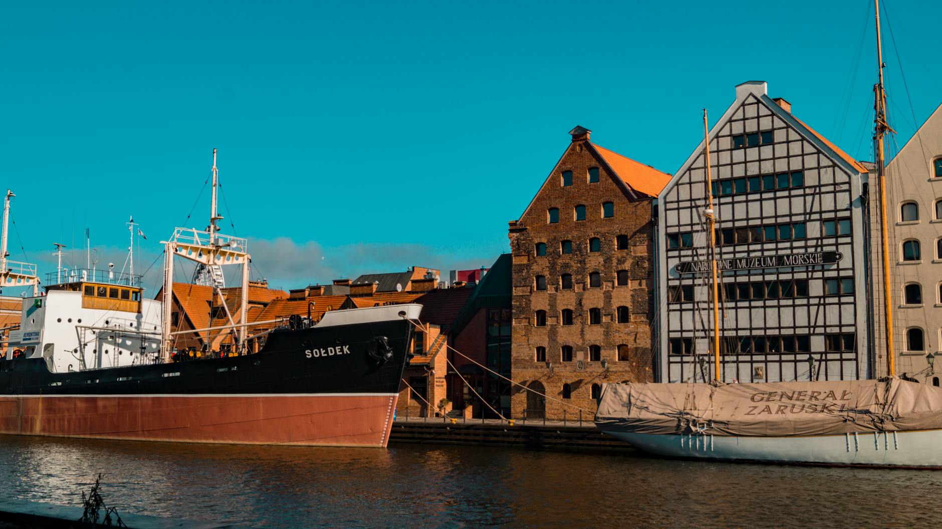 Zabytkowe statki przy nabrzeżu przed historyczną zabudową Gdańska