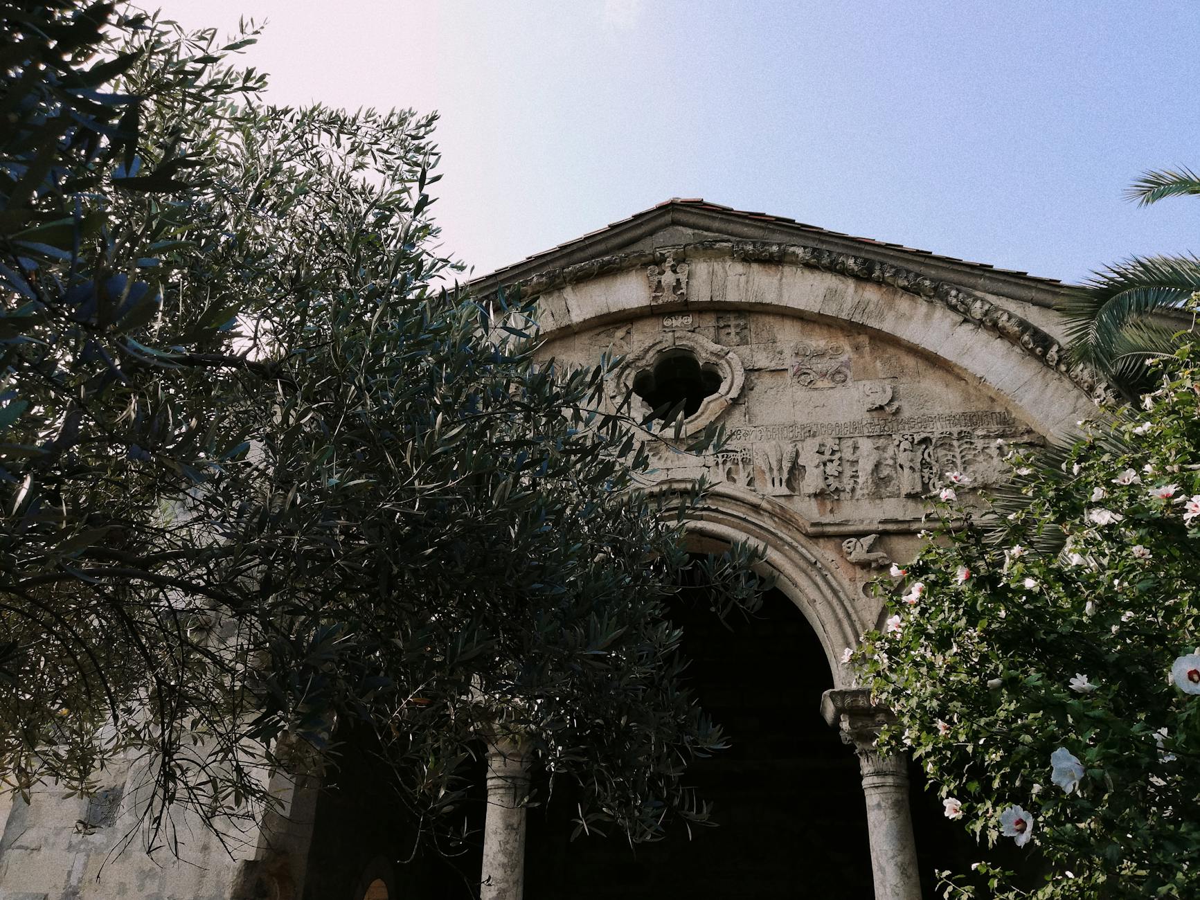 Fasada zabytkowego kościoła z rzeźbami, otoczona zielenią