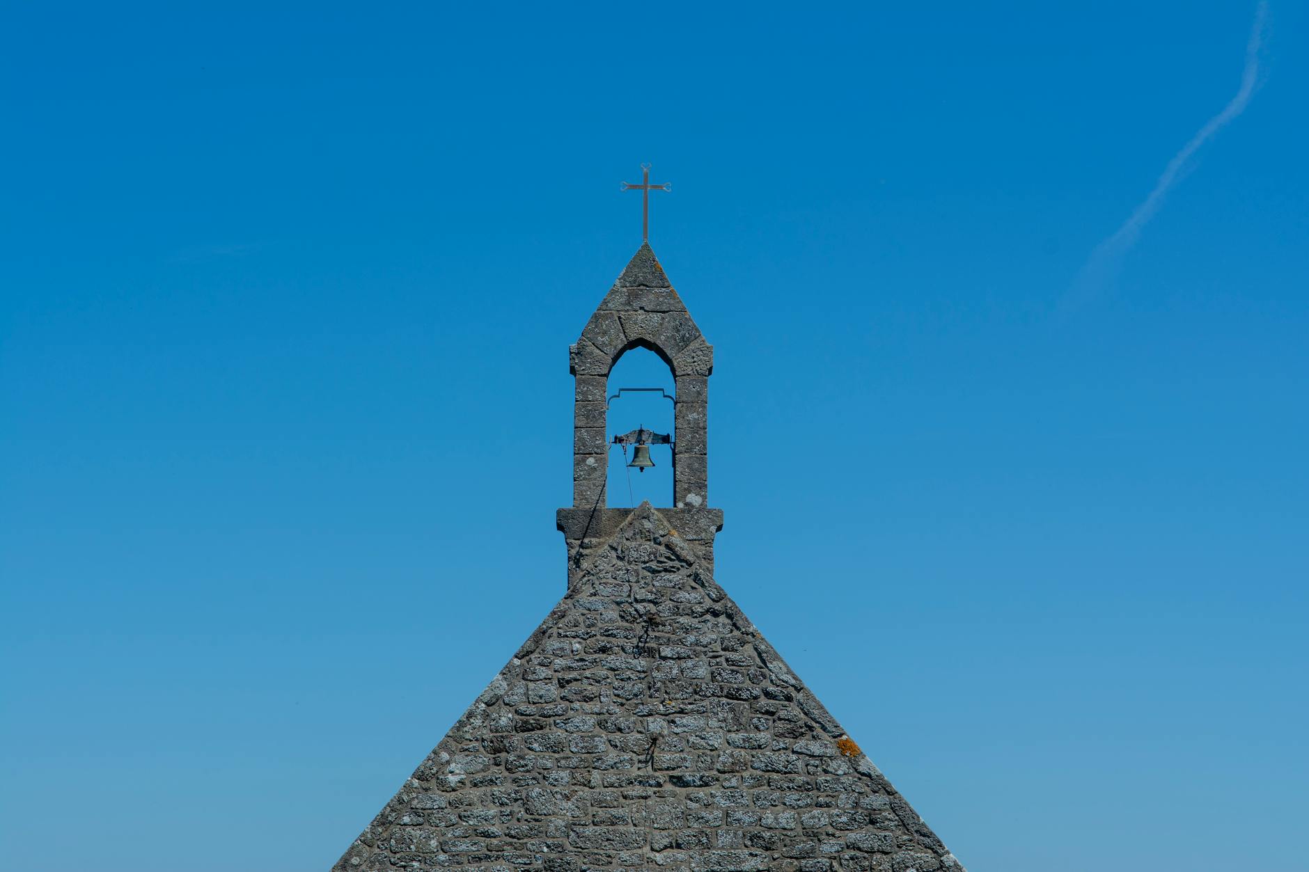 Kamienna wieża dzwonnicy kaplicy na tle czystego błękitnego nieba