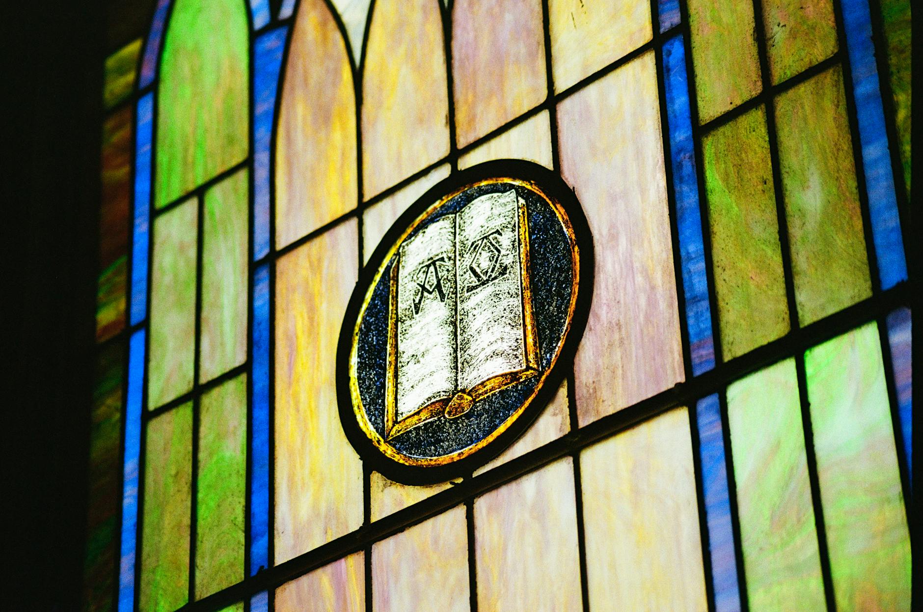 Kolorowy witraż z symbolem księgi w kościele Fara w Ciechanowie