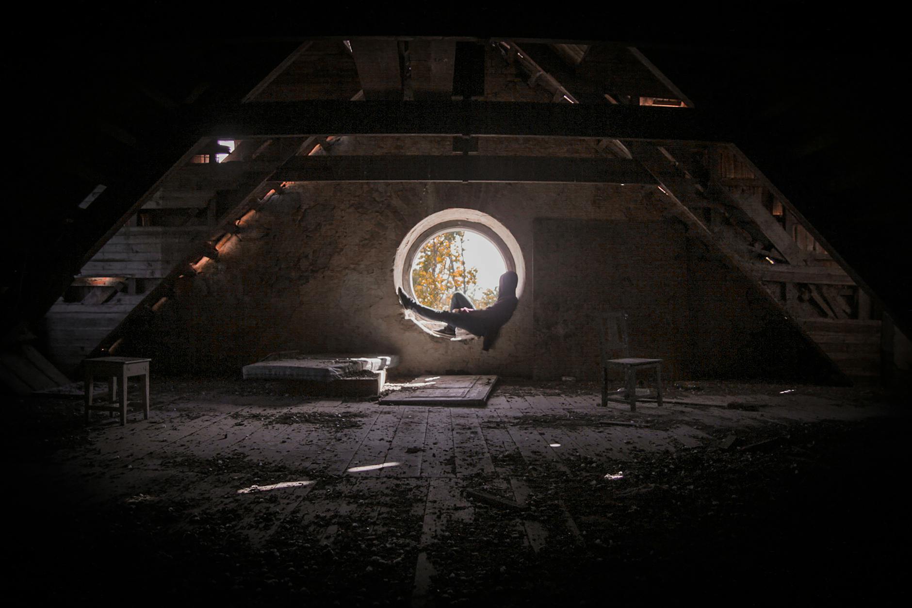 Osoba siedząca w oknie poddasza w ciepłym jesiennym świetle