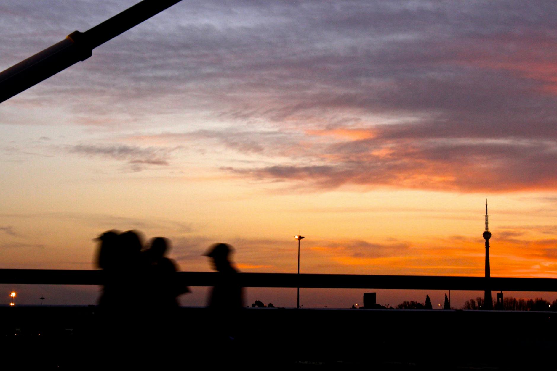 Sylwetki spacerowiczów na tle złotego zachodu słońca