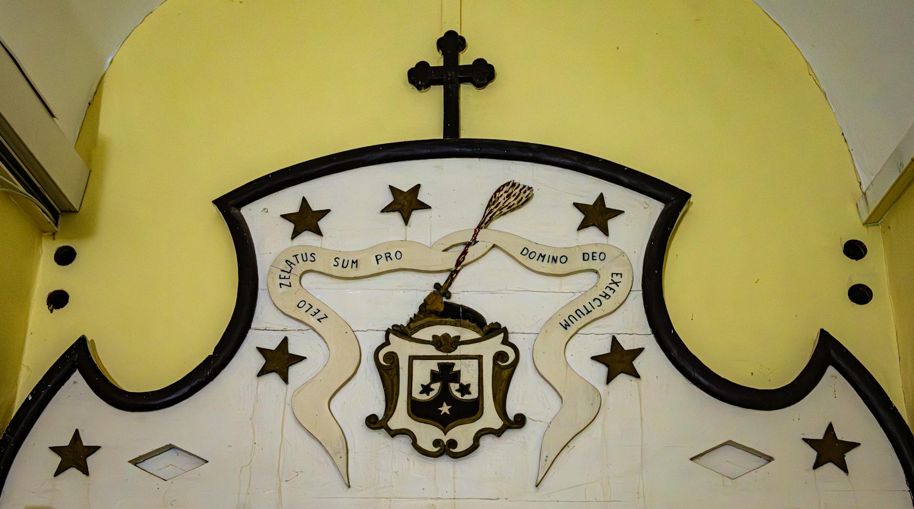 Dekoracyjna tablica z łacińskim napisem i symbolami w farze w Ciechanowie