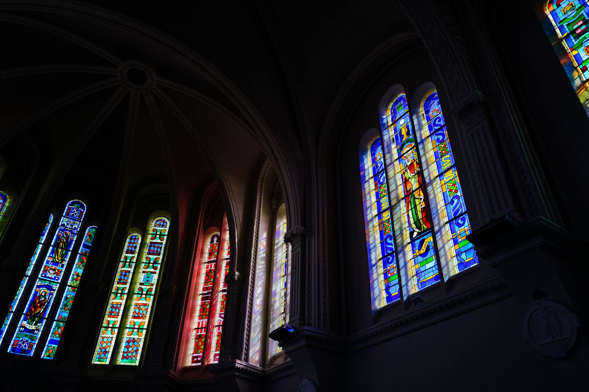 Kolorowe witraże z motywami religijnymi we wnętrzu fary