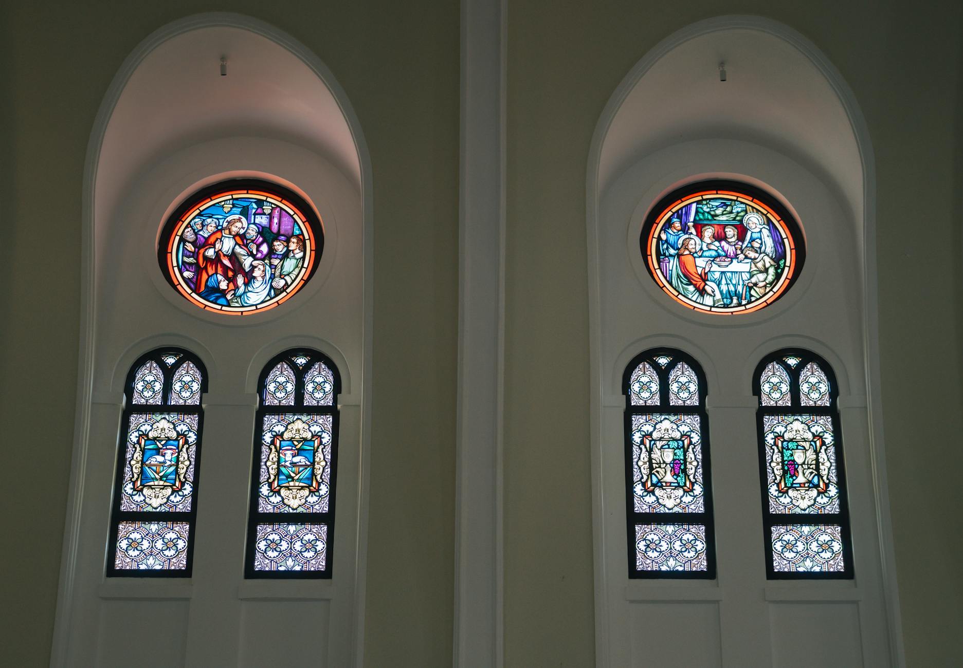 Wnętrze Fary w Ciechanowie z barwnymi witrażami o tematyce religijnej