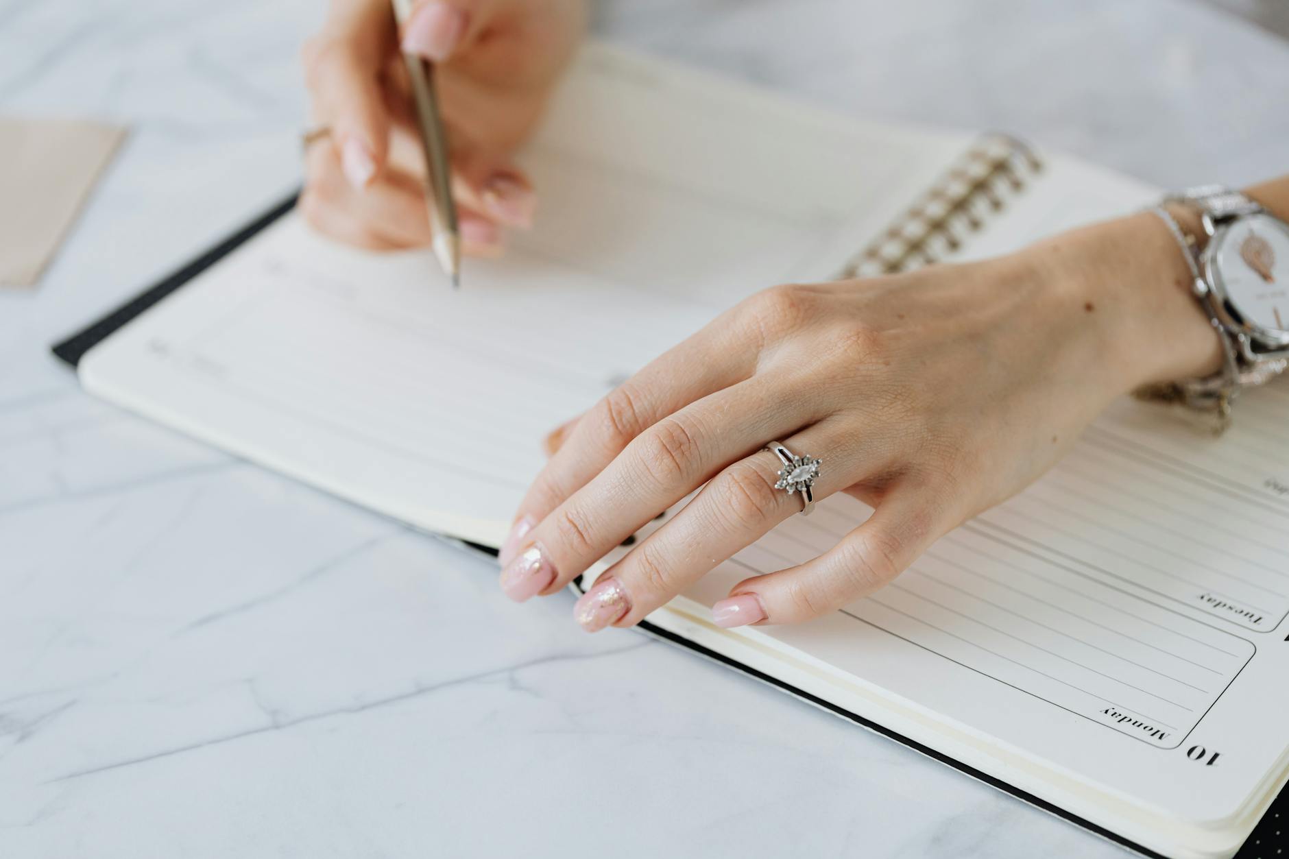 Zbliżenie dłoni zapisujących plan wesela w notesie
