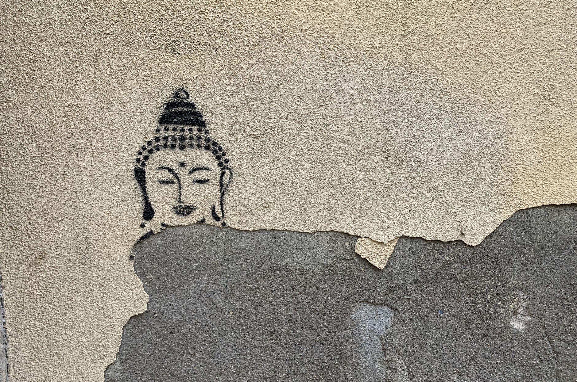 Głowa Buddy w graffiti na łuszczącej się ścianie w Weronie