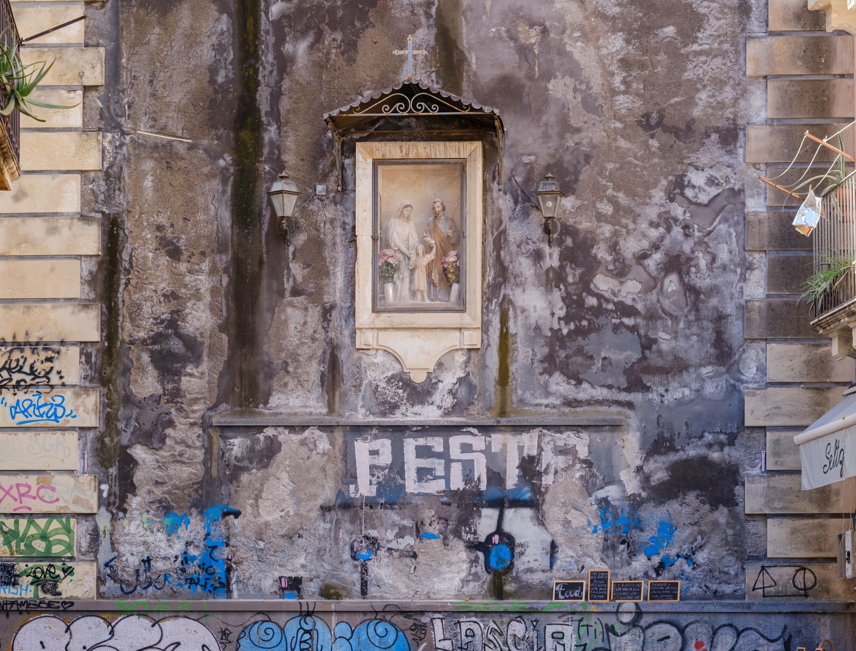 Stara ściana z religijnym freskiem i dawnym graffiti